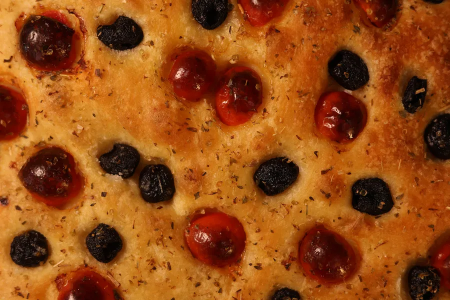 Détail de la focaccia : tomates, olives et croûte dorée